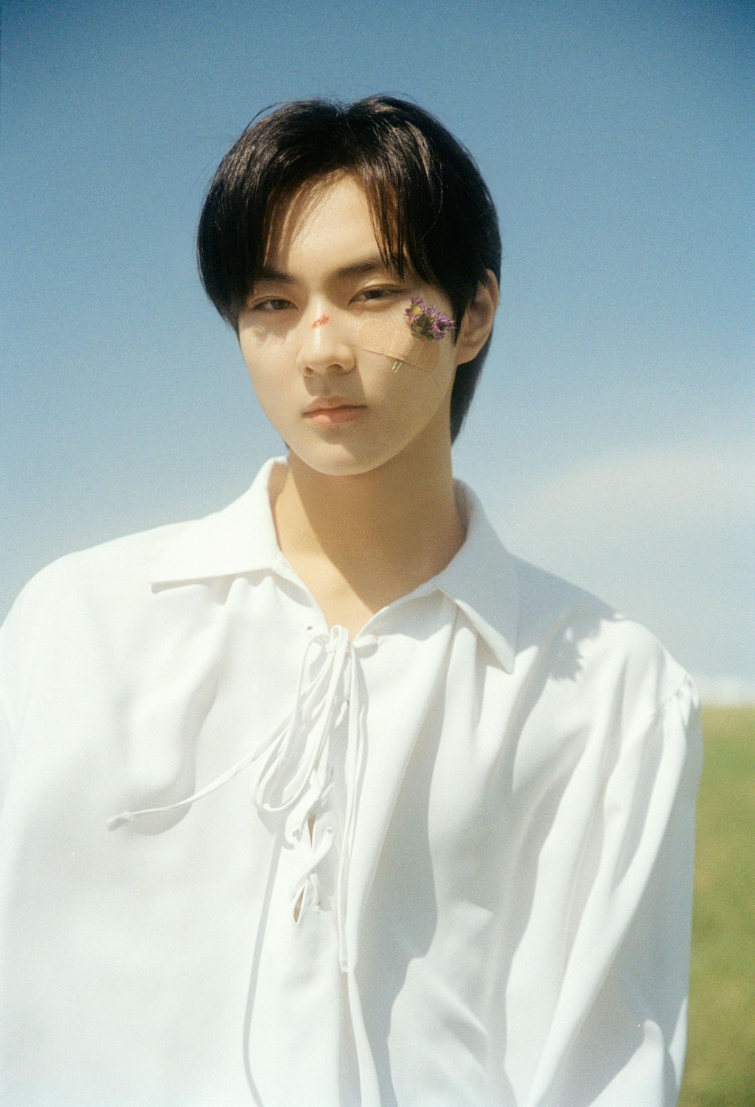 a man in a white shirt with a flower on his forehead