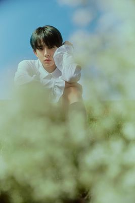 a boy sitting in the grass with his hands on his head