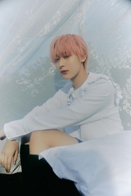 a man with pink hair sitting on a bed