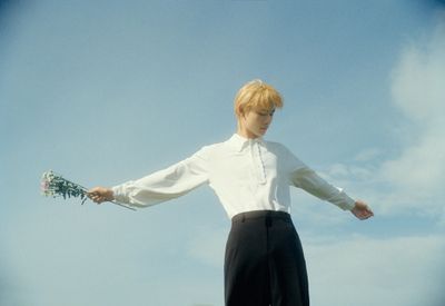 a man in a white shirt and black pants holding a bunch of flowers