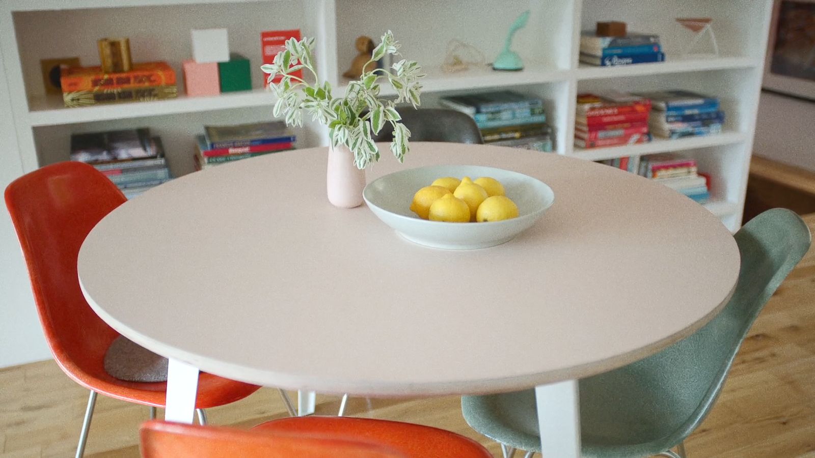 a bowl of lemons sits on a table in front of a bookcase