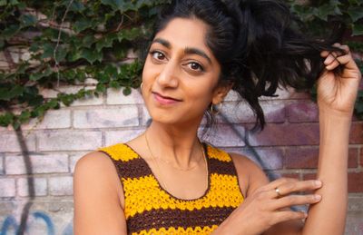 a woman in a yellow and brown dress is holding her hair