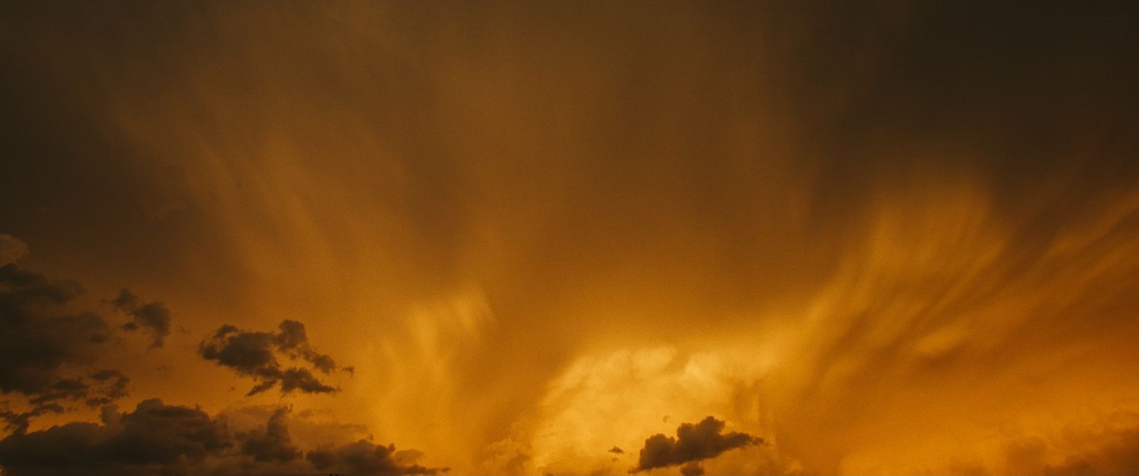 a plane flying through a cloudy sky at sunset