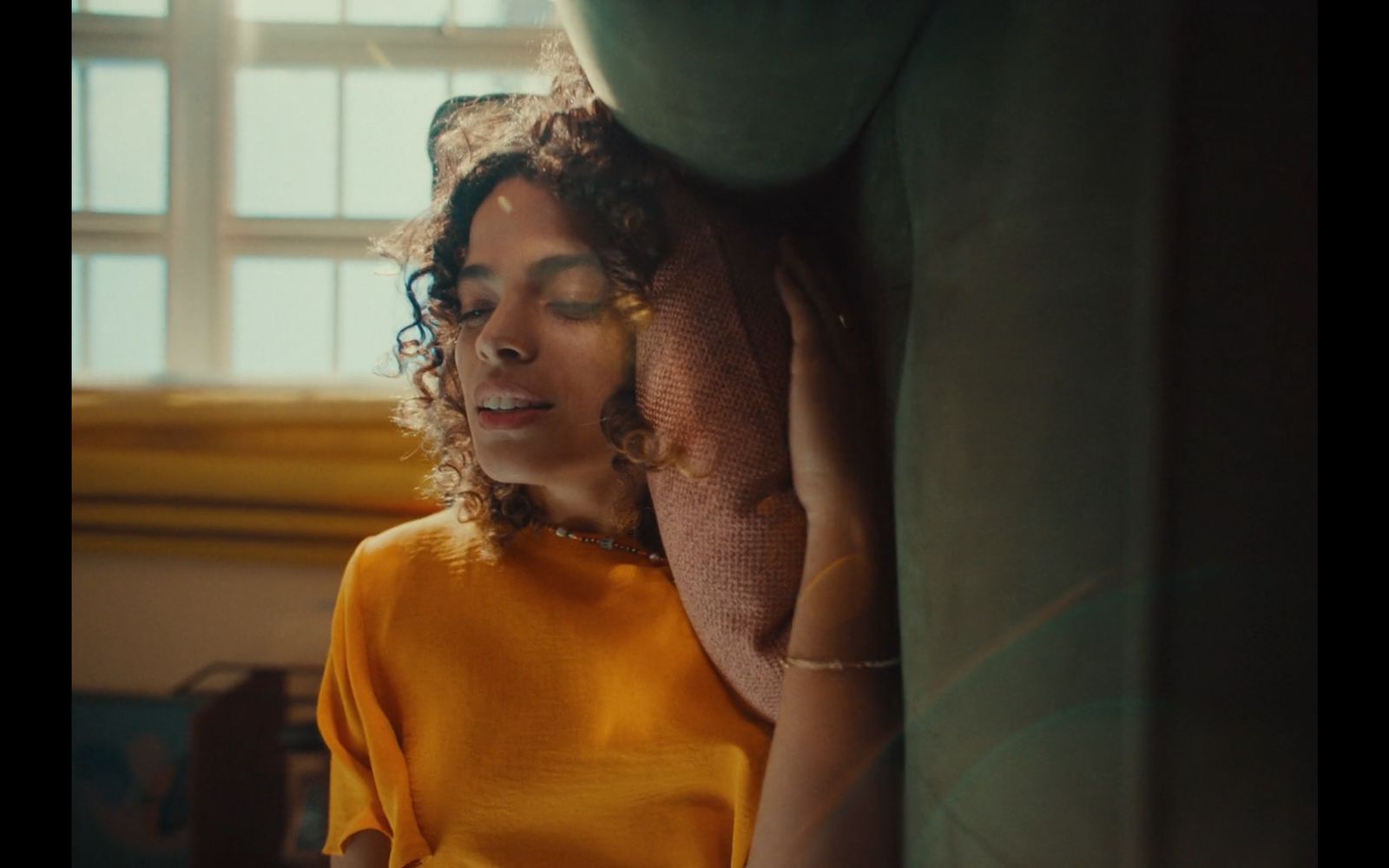 a woman in a yellow shirt leaning against a wall