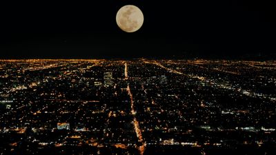 a full moon over a city at night