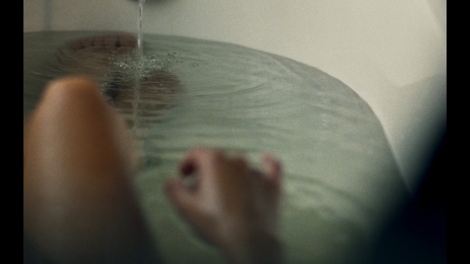 a person sitting in a bathtub with their feet in the water