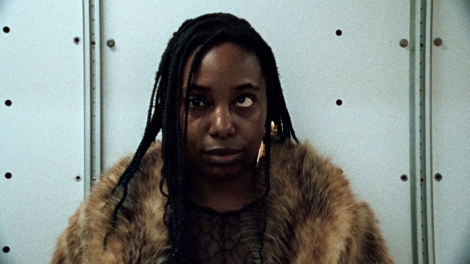 a woman with dreadlocks standing in front of a wall