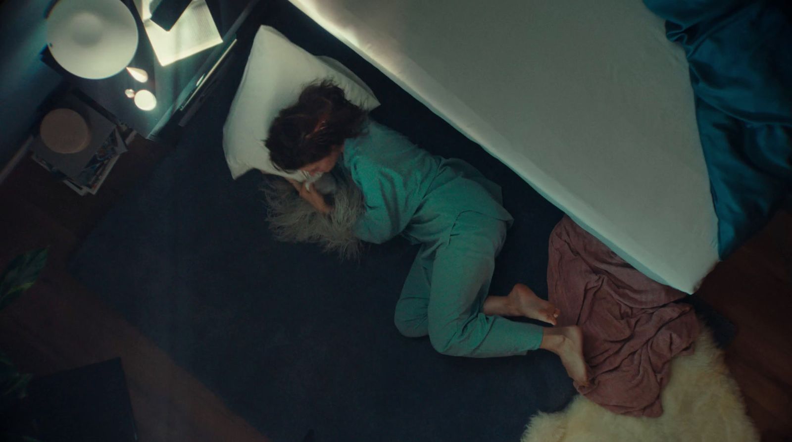 a woman laying on the floor next to a bed