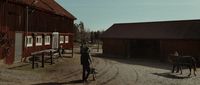 a man standing next to a horse in front of a barn