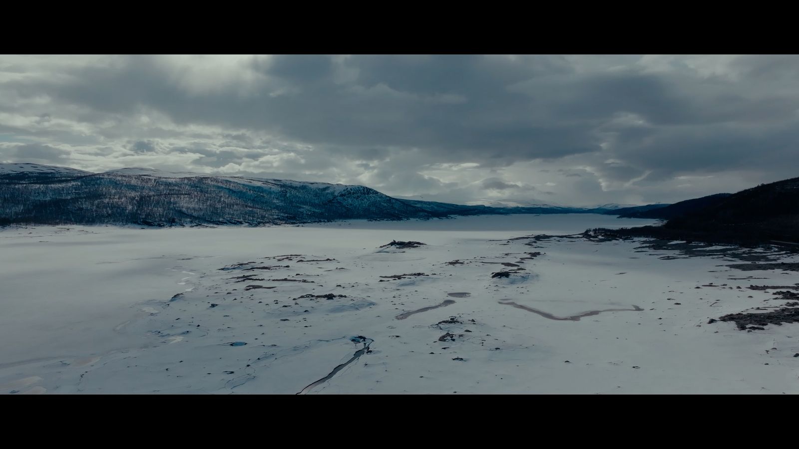 an aerial view of a snowy landscape with mountains in the distance