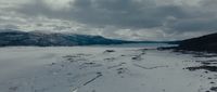 a snow covered field with mountains in the background