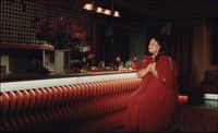 a woman in a red dress standing at a bar