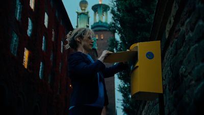 a woman in a blue jacket is holding a yellow box