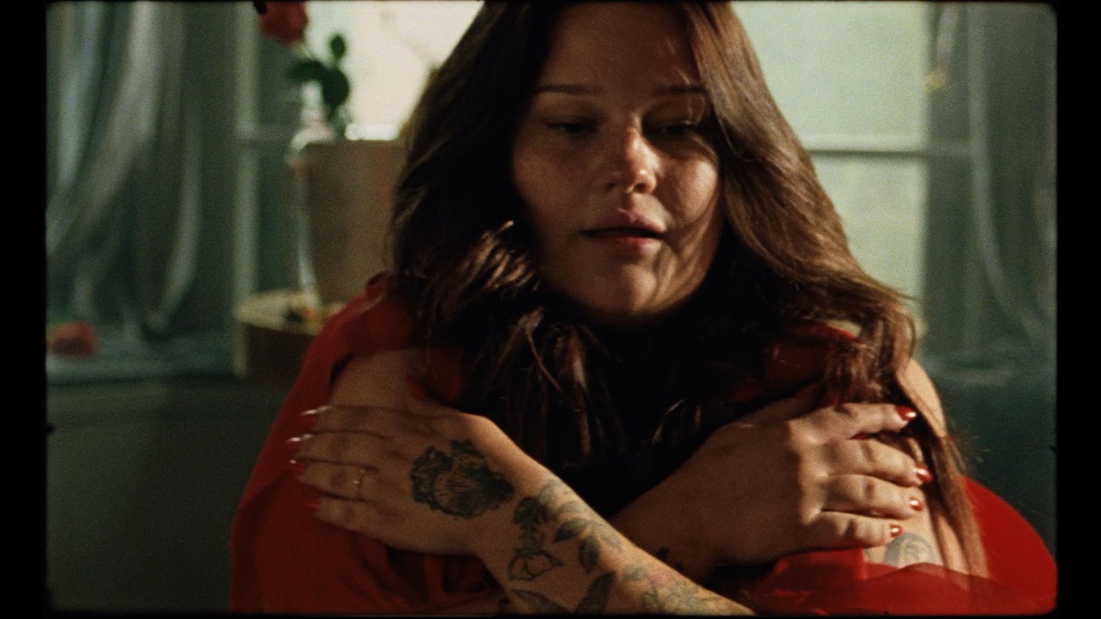 a woman in a red shirt holding a tattoo on her arm