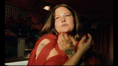 a woman in a red shirt with tattoos on her chest