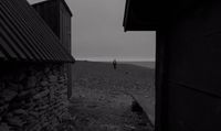 a black and white photo of a person walking down a hill