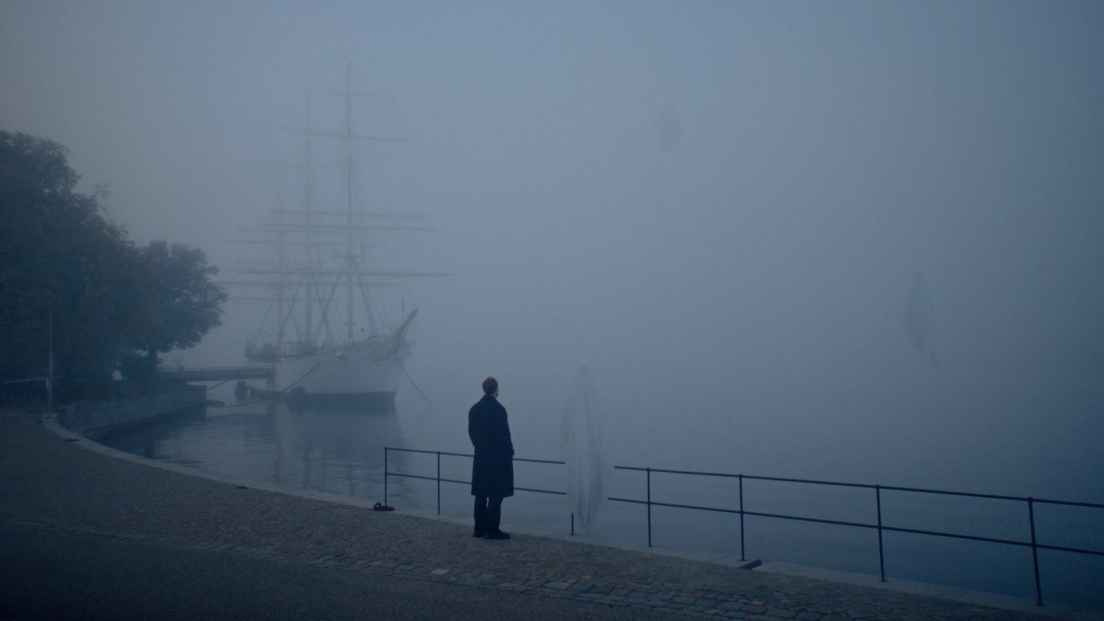 a person standing in front of a boat on a foggy day