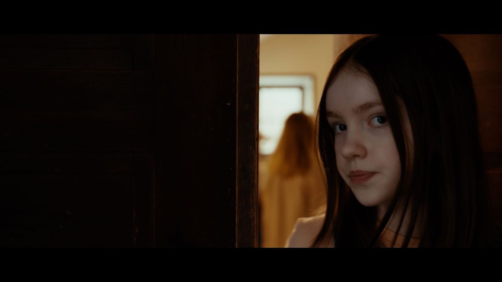 a woman with long hair standing in front of a door