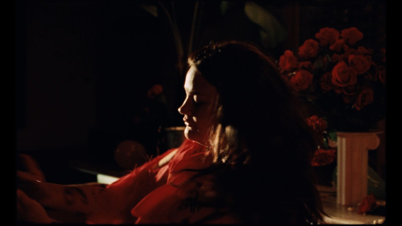 a woman in a red dress sitting in a dark room