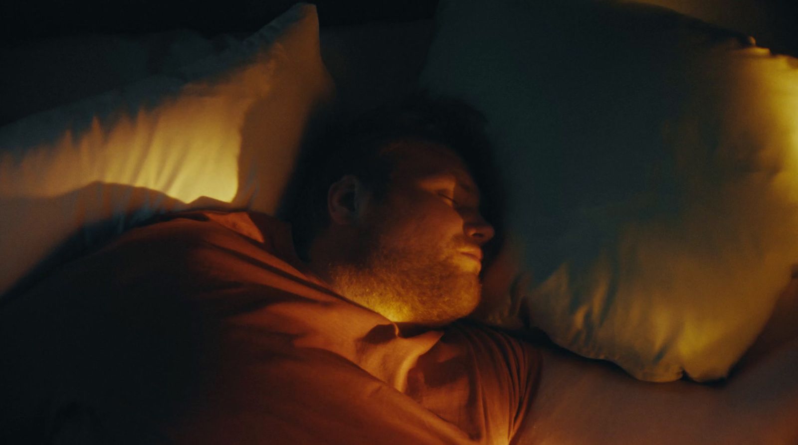 a man laying in bed with his eyes closed