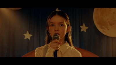 a woman holding a microphone in front of a curtain