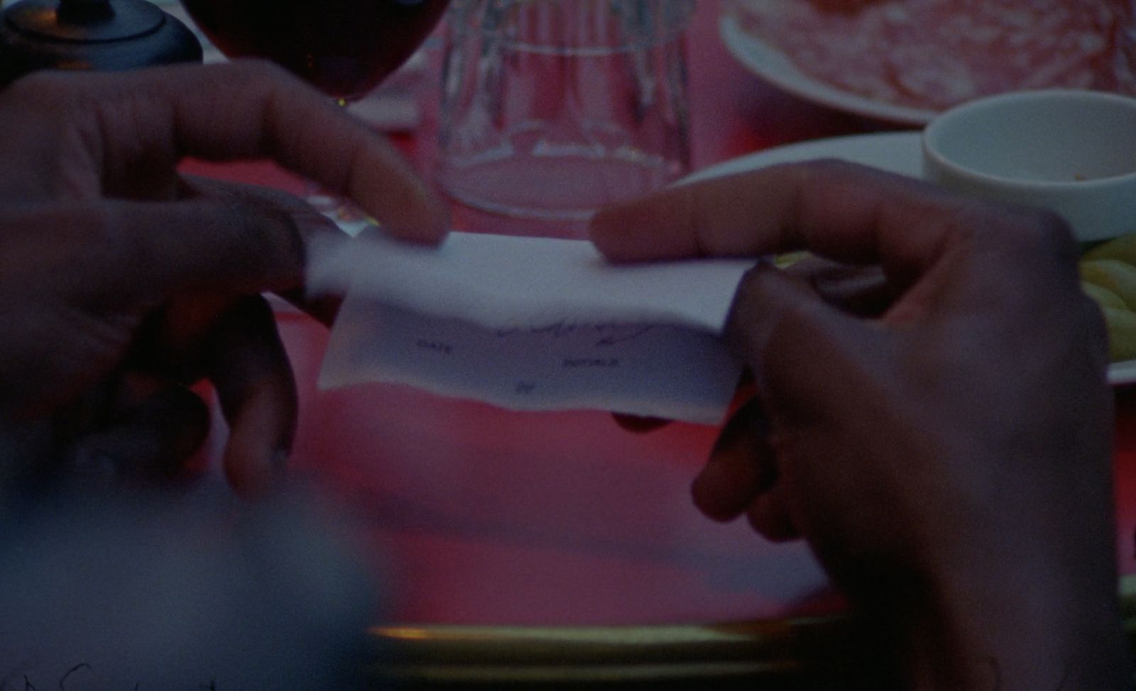 two hands holding a piece of paper at a table