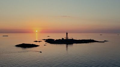 the sun is setting over a small island in the middle of the ocean