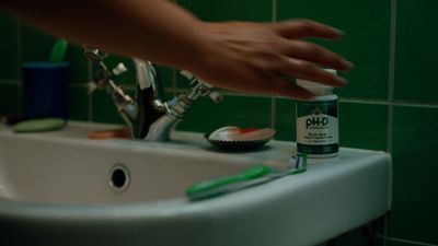 a person reaching for toothbrushes in a bathroom sink