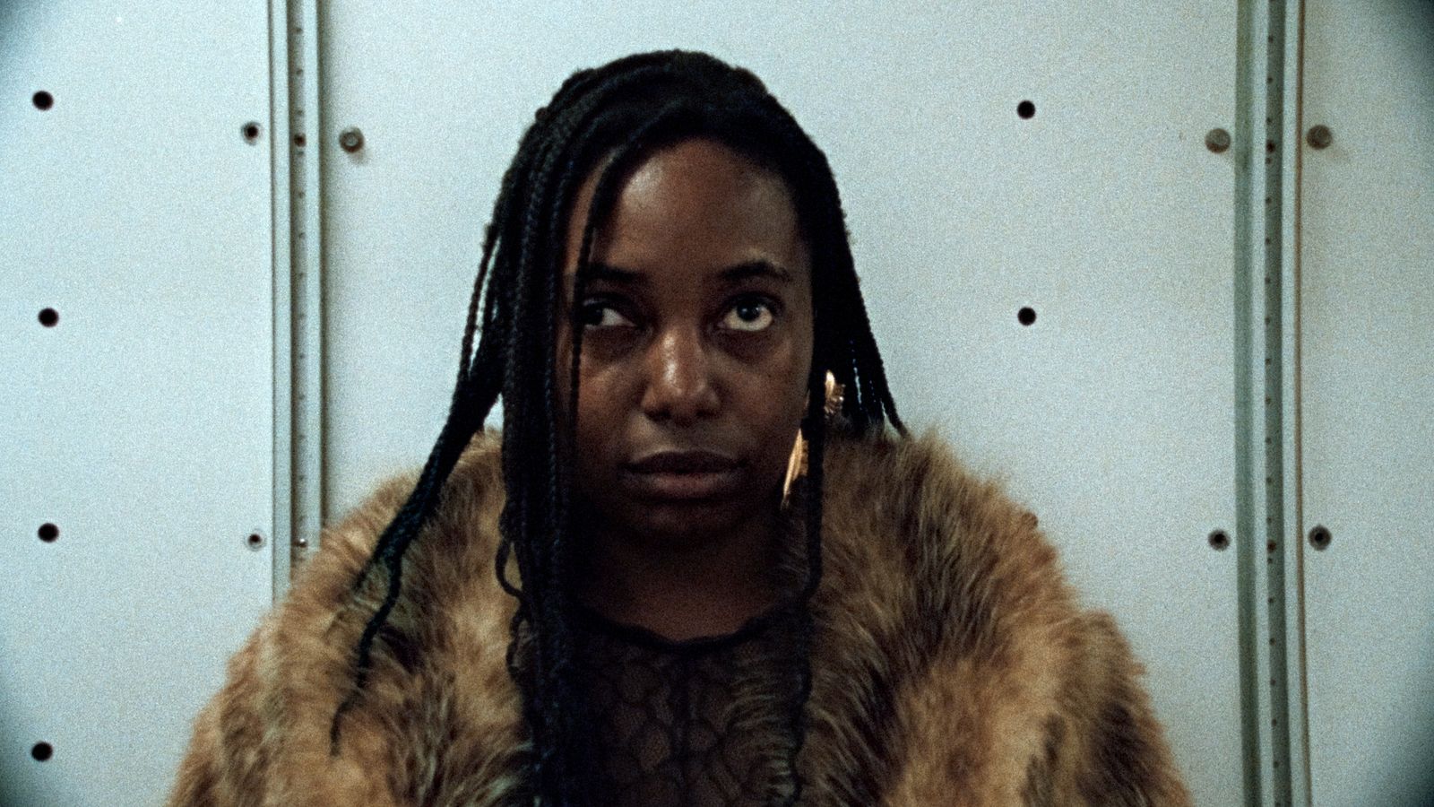 a woman with dreadlocks standing in front of a wall