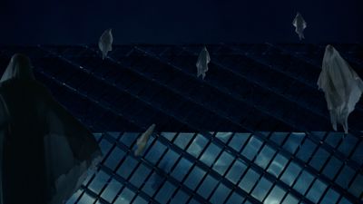 a group of bats flying over a building at night