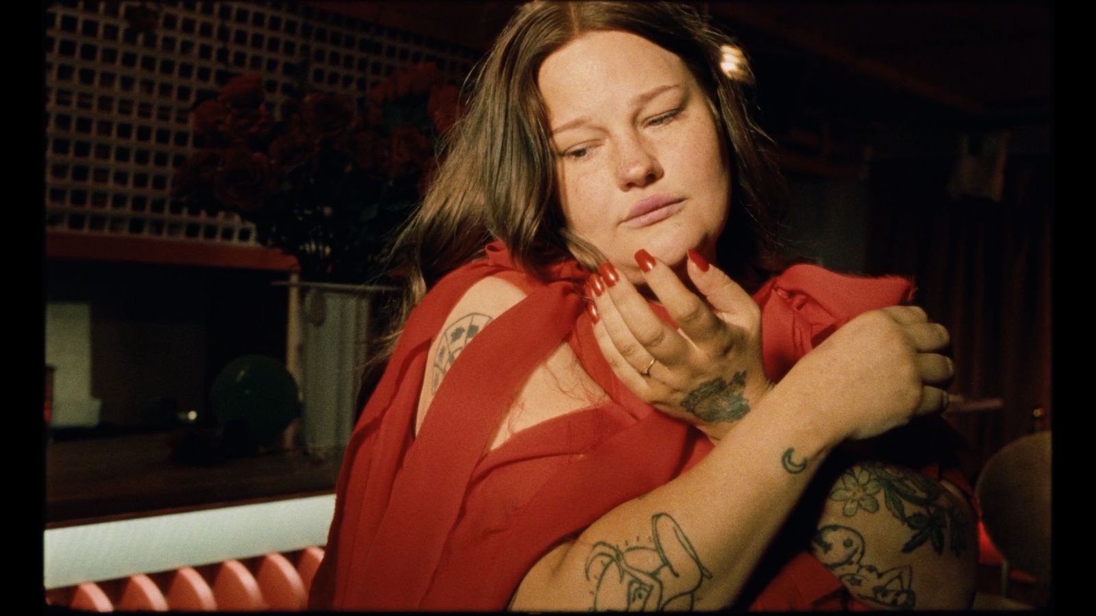 a woman in a red shirt with tattoos on her arm