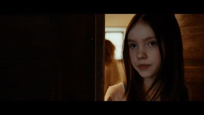 a girl with long hair standing in front of a door