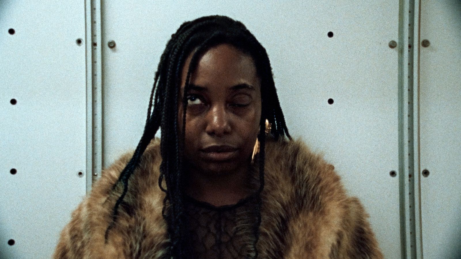 a woman with dreadlocks standing in front of a wall