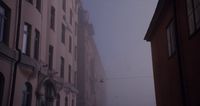 a foggy city street with tall buildings