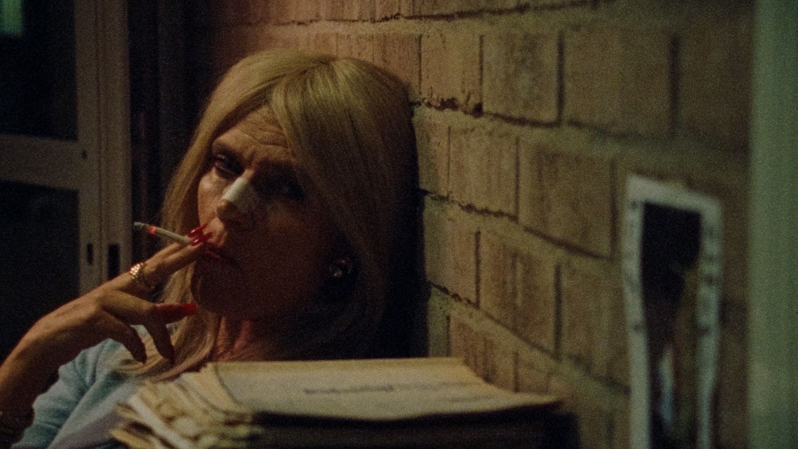 a woman smoking a cigarette next to a stack of books