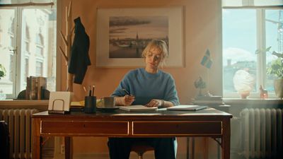 a woman sitting at a desk writing on a piece of paper