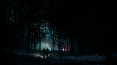 two people walking through a dark forest at night