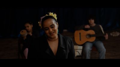 a woman with a flower in her hair playing a guitar