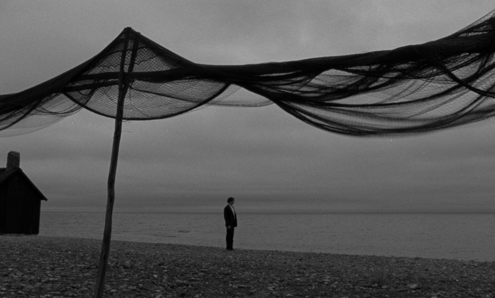 a black and white photo of a man standing on a beach