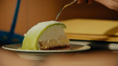 a person cutting into a piece of cake on a plate