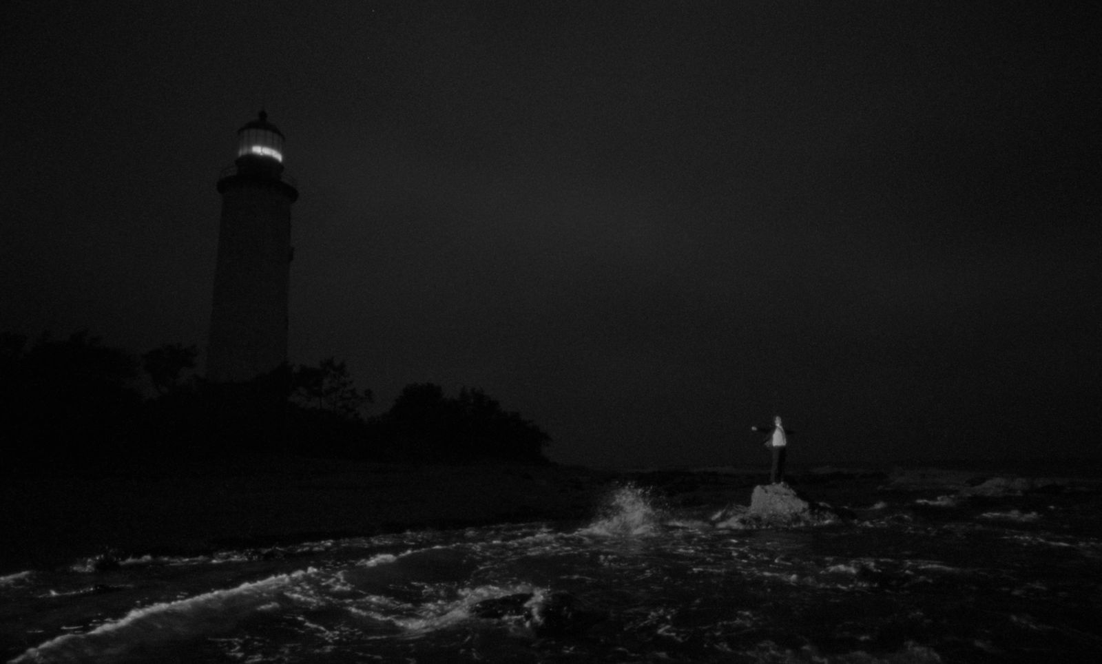 a black and white photo of a lighthouse at night