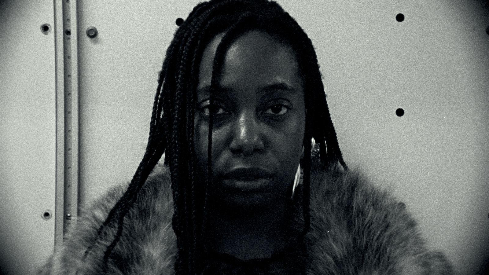 a woman with dreadlocks wearing a fur coat