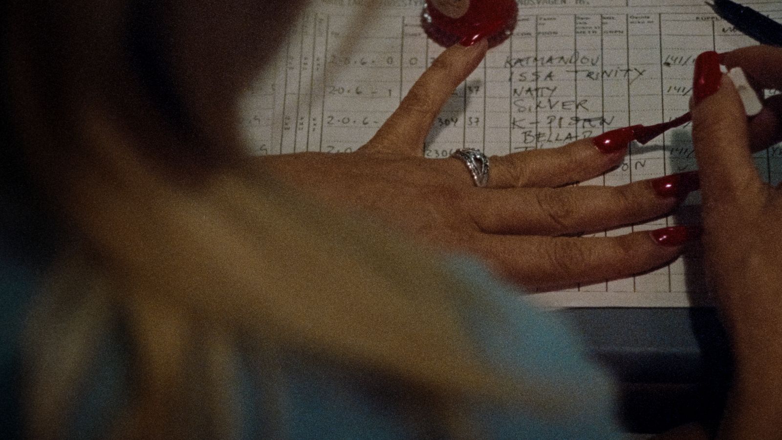 a woman with red nails writing on a piece of paper