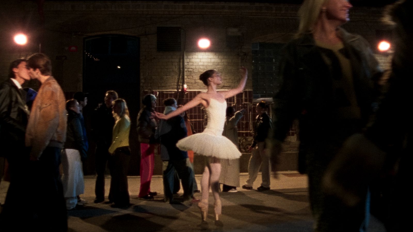 a woman in a white tutu dancing in front of a crowd of people