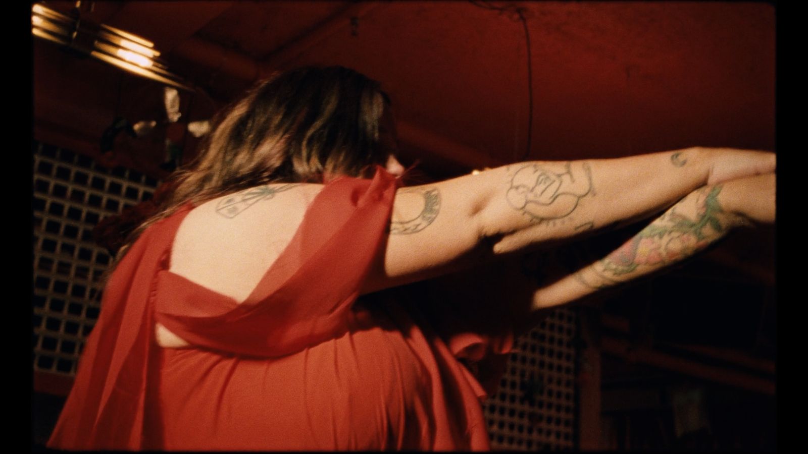 a woman in a red dress with tattoos on her arm