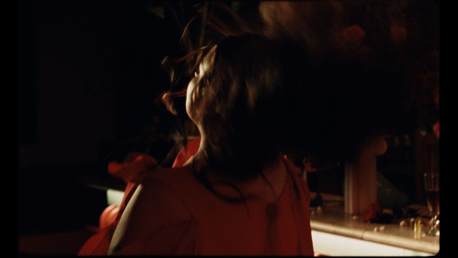 a woman standing in front of a bar in the dark