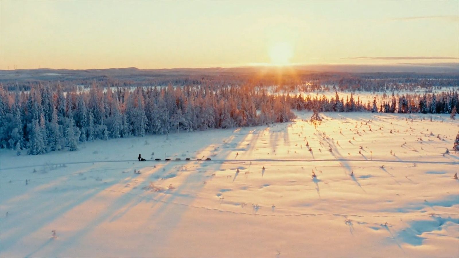 the sun is setting over a snow covered field