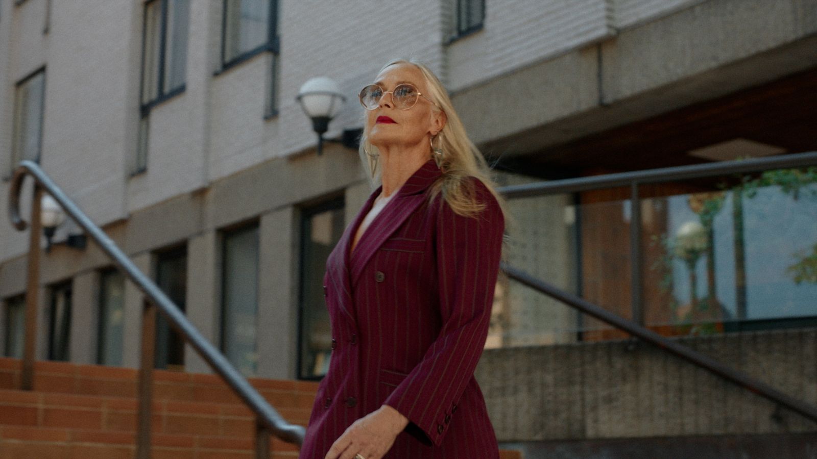 a woman in a suit and sunglasses walking down the street