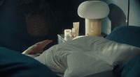 a person laying in a bed with a night stand