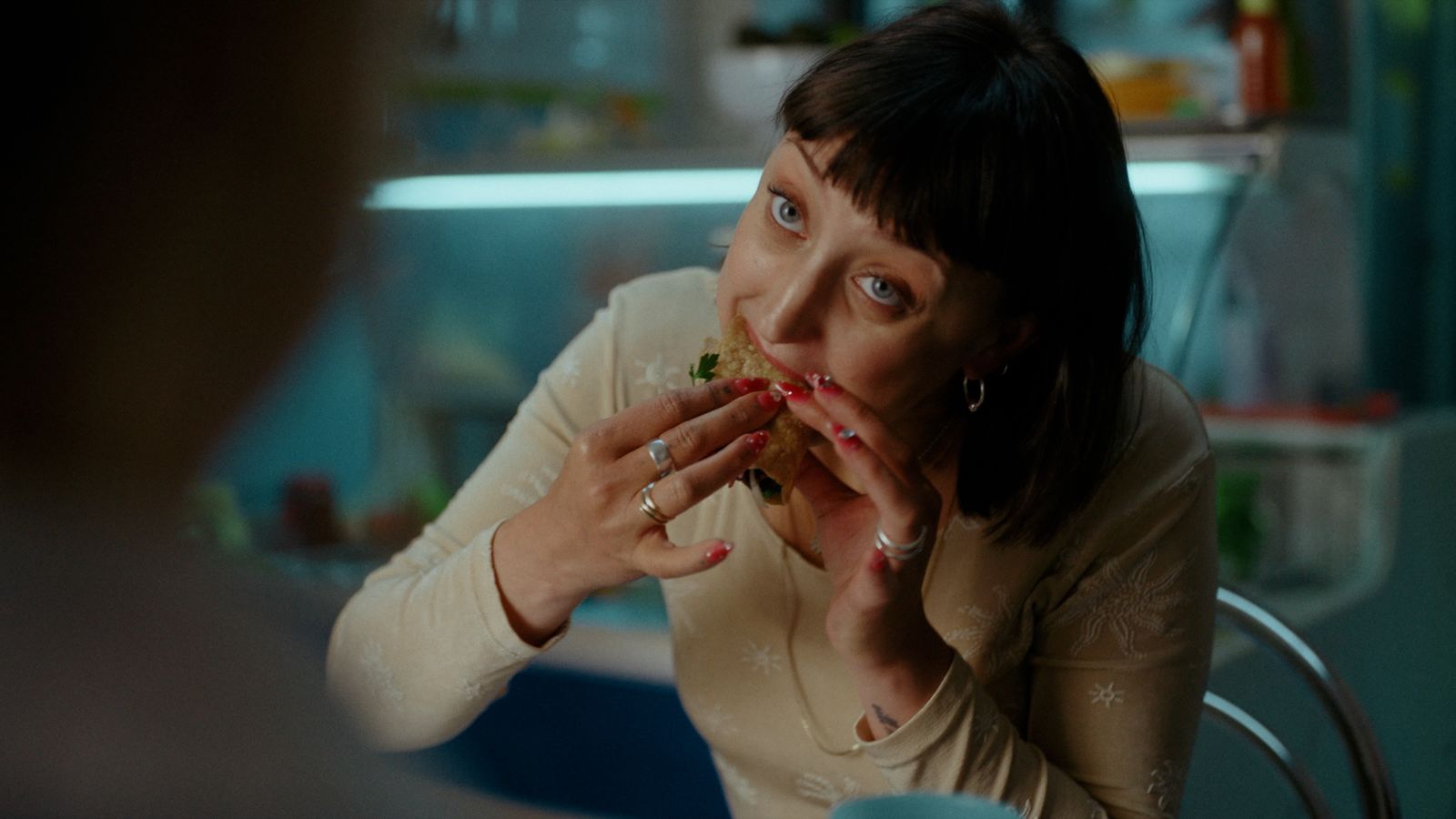 a woman sitting at a table eating a sandwich